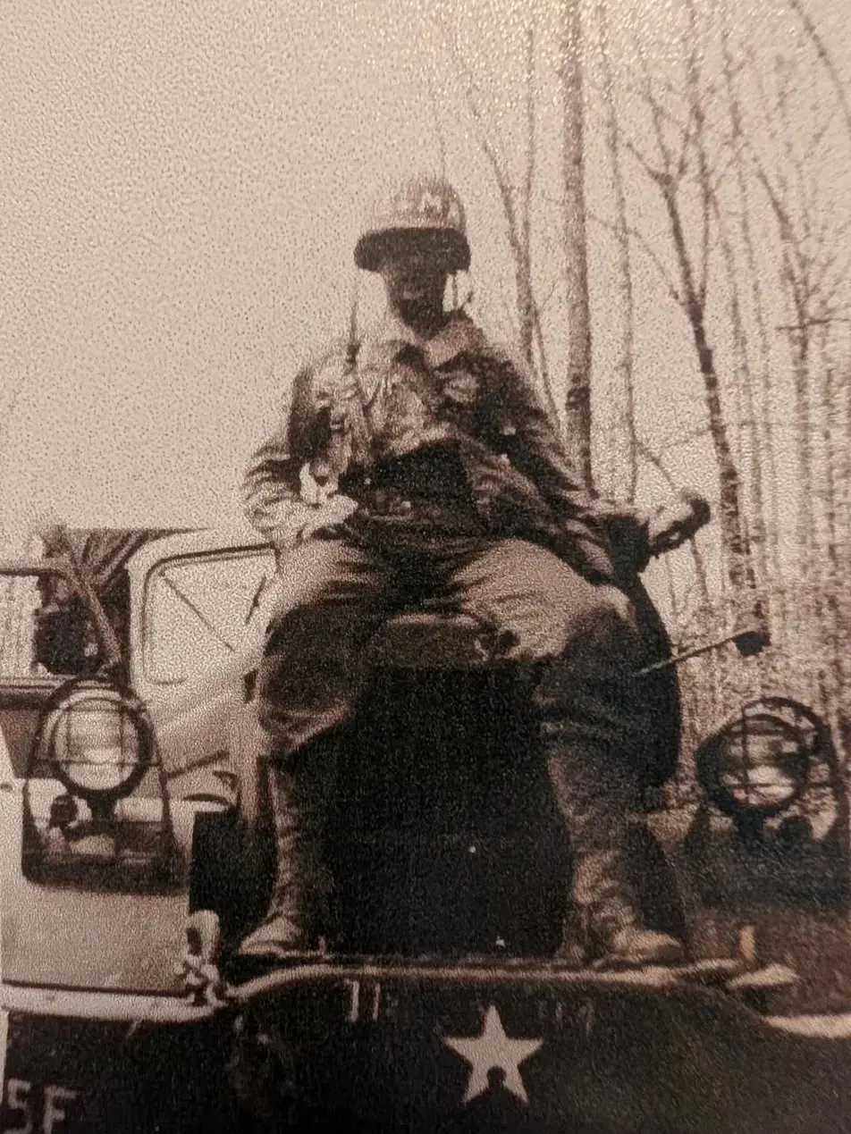 Everett Schafer seated on a vehicle, his helmet marked with the name Elma, his wife's name